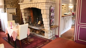Un comedor con chimenea de piedra, una mesa con mantel rosa y alfombra roja.