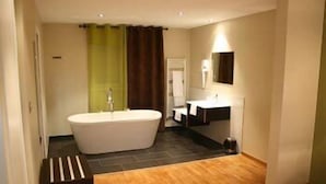Un baño moderno con una bañera independiente, un tocador con espejo y una zona de ducha.