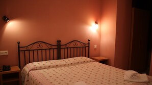Een slaapkamer met twee bedden, elk met een bloemenprint beddeken en een netjes gevouwen handdoek op het bed.