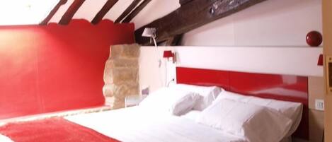 Una habitación con una cama, un pilar de piedra y una decoración en colores rojo y blanco.