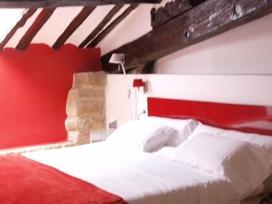 Una habitación con una cama, un pilar de piedra y una decoración en colores rojo y blanco.