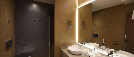 A modern bathroom with two sinks, a large mirror, and a shower area.