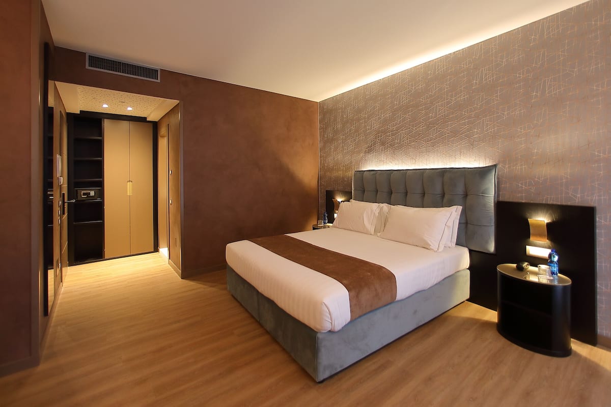 Een moderne hotelkamer met een groot bed, een nachtkastje met een lamp en een kledingkast.