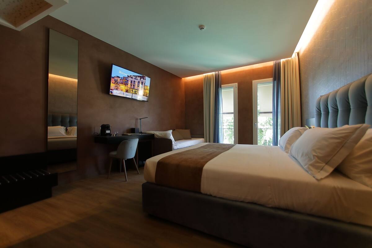 Hotelkamer met een groot bed, een bureau, een stoel, een televisie en een raam.