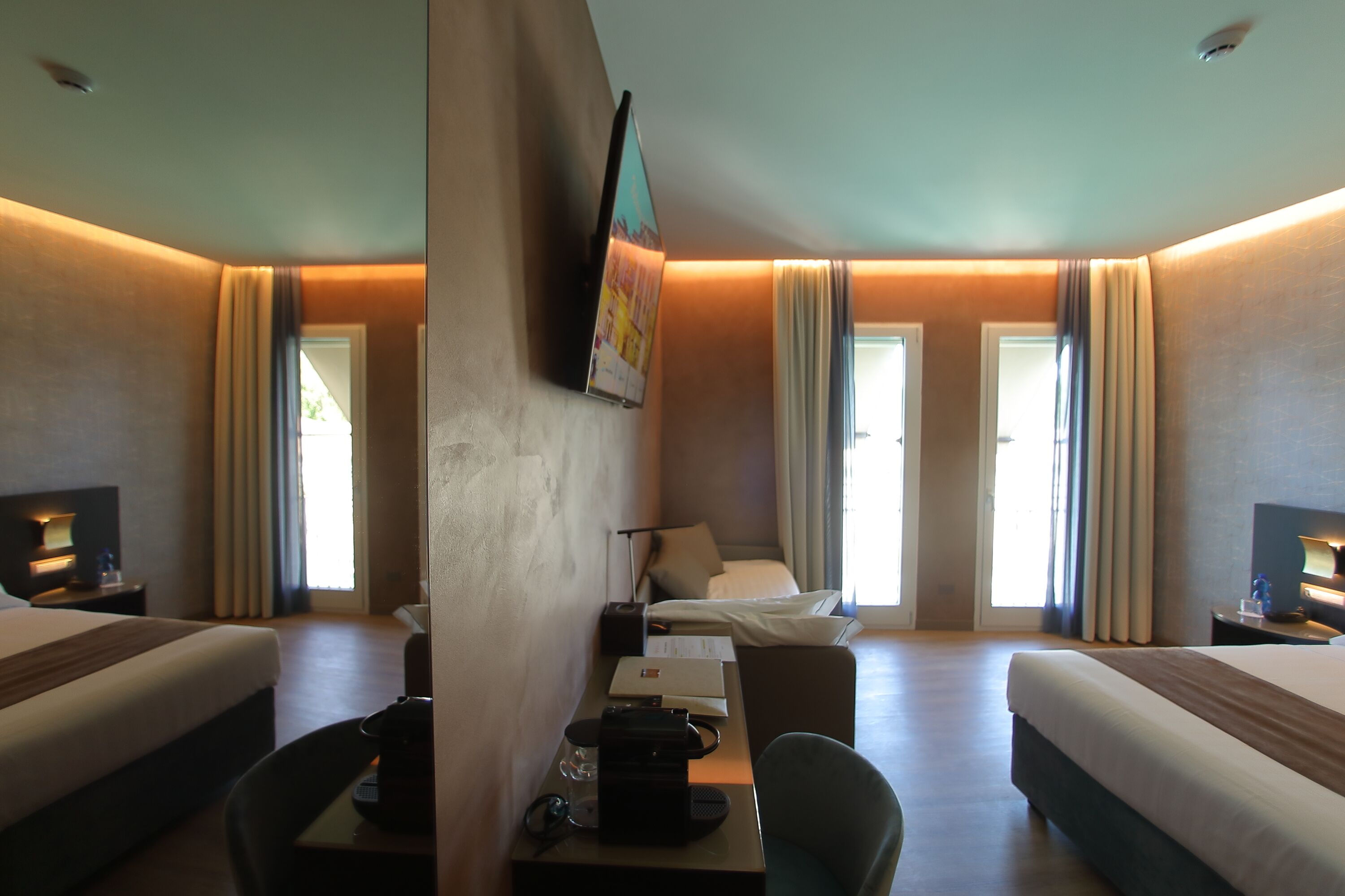 Habitación de hotel con dos camas, un escritorio, una silla, un televisor y una ventana con cortinas.