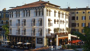 Un hôtel doté d’une terrasse, d’un balcon et d’une enseigne indiquant « Hôtel Bell’Arrivo ».