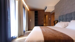 Une chambre d’hôtel avec un grand lit, une armoire et une salle de bain visible à travers une porte ouverte.