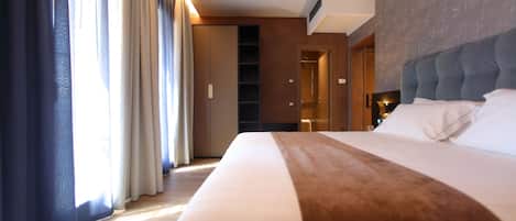 Une chambre d’hôtel avec un grand lit, une armoire et une salle de bain visible à travers une porte ouverte.