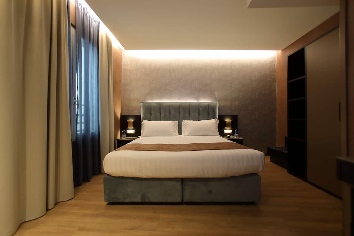 Een moderne slaapkamer met een groot bed, bedlampjes en een kledingkast.