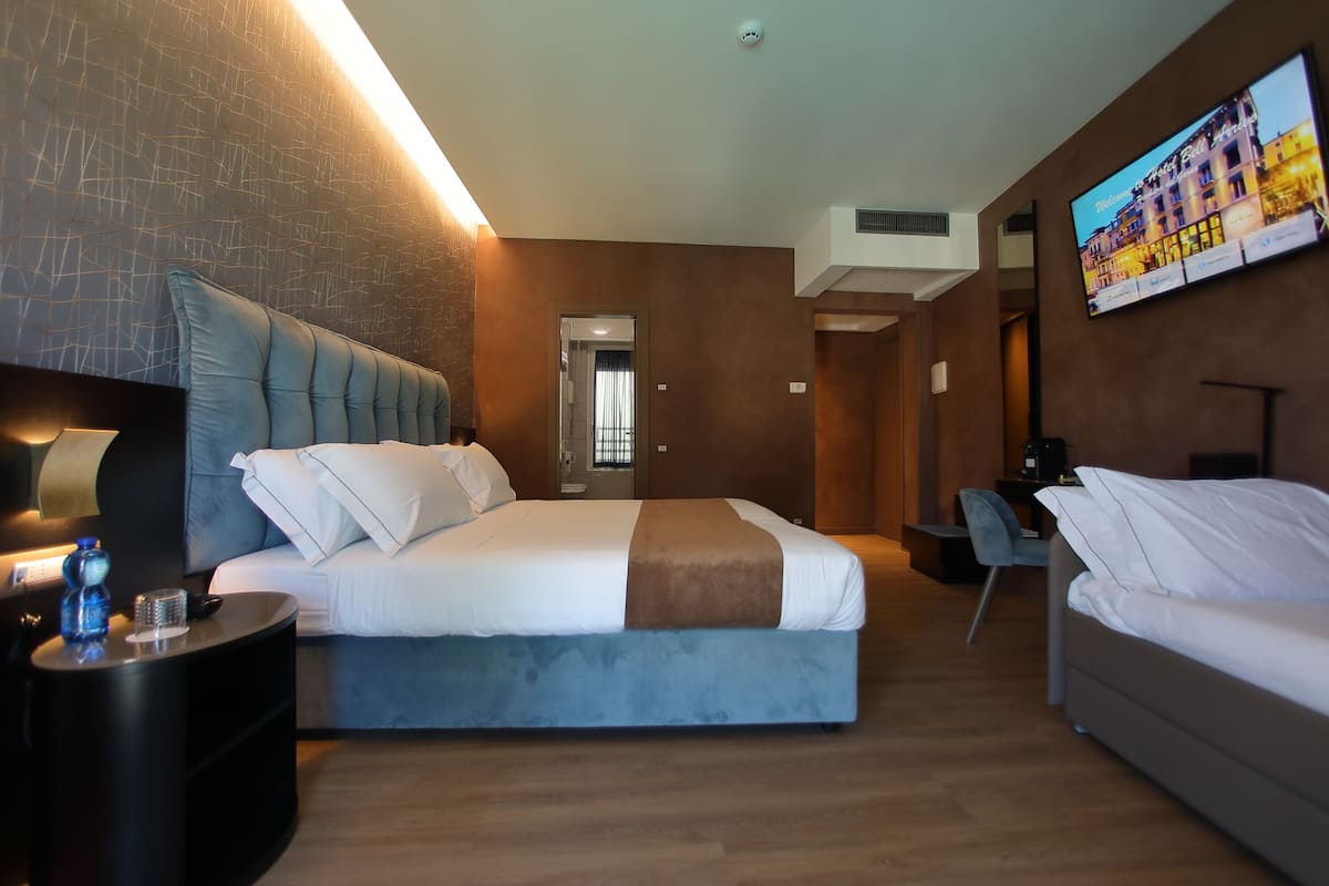 Een moderne hotelkamer met een groot bed, een bureau en een televisie aan de muur.