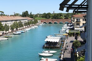 Un canal bordé de bateaux amarrés, un pont en arrière-plan et des bâtiments dotés de balcons donnant sur l’eau.