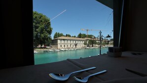Une table avec des couverts et une vue sur une marina, avec des bateaux et un bâtiment en arrière-plan.