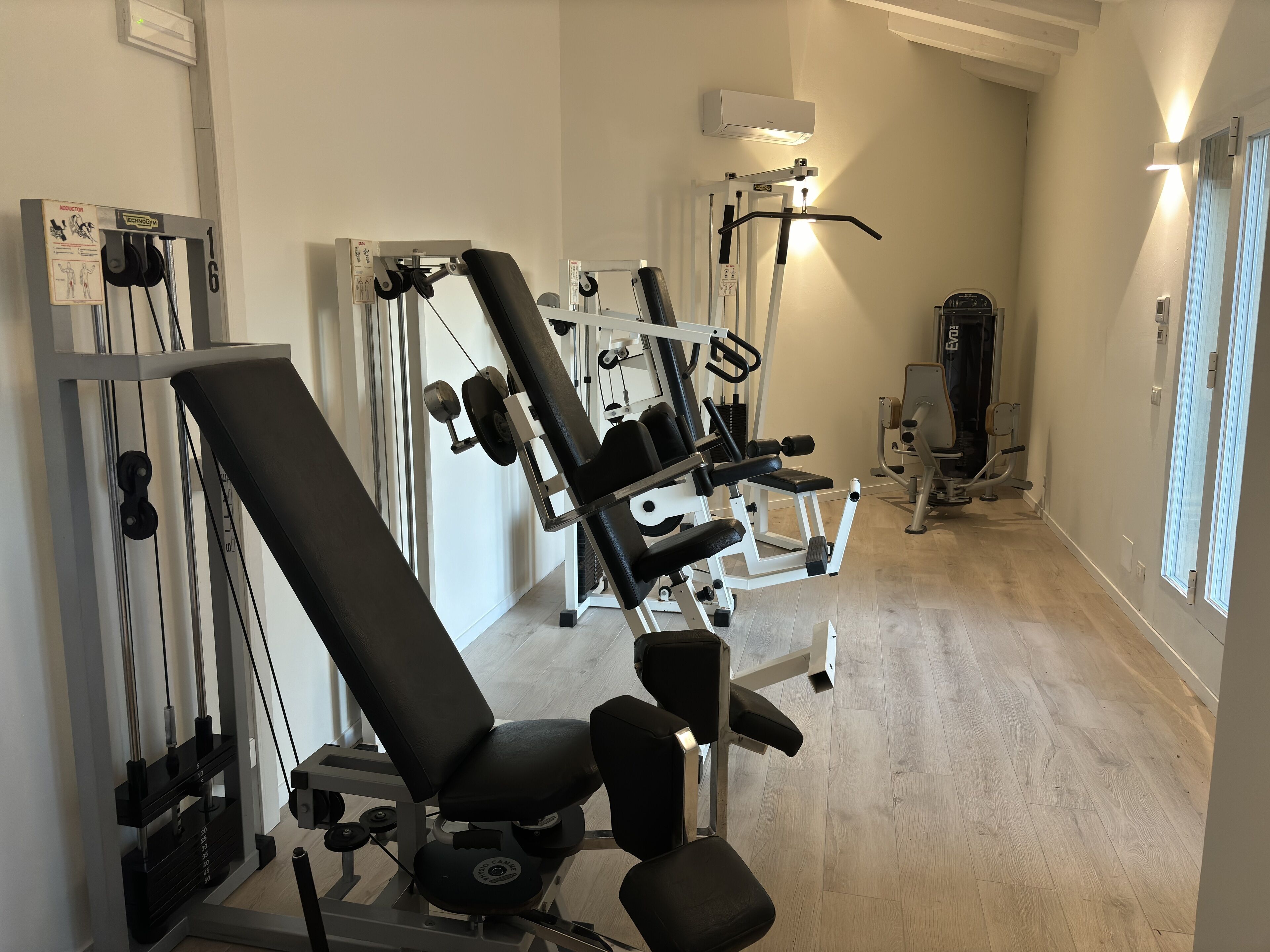 Une salle de sport équipée de divers appareils d’entraînement, notamment un banc de développé couché, des haltères et une machine à câbles.
