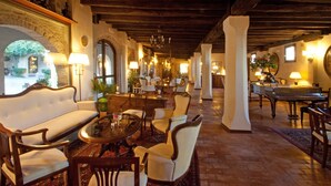 Un salón amplio y elegantemente amoblado, con techo alto, asientos cómodos y vista al patio.
