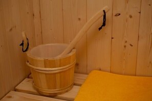 A wooden sauna with a wooden bucket and a long wooden handle.