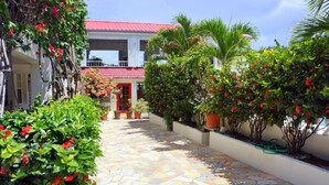 Un patio empedrado con macetas y plantas, y un edificio con techo rojo.