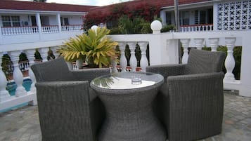 A patio area with wicker furniture, a round table, and a white balustrade.