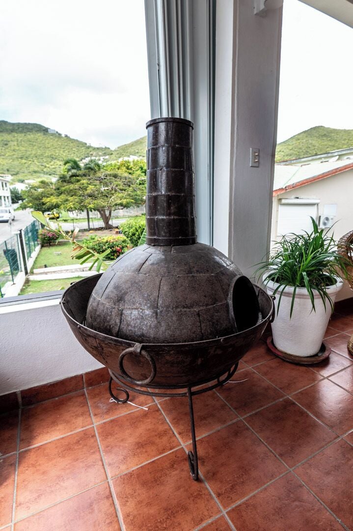 A traditional wood-fired oven on a balcony with a view of a green landscape.