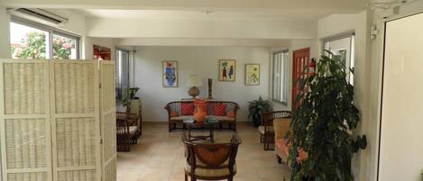 A spacious living area with a sofa set, a dining table, and a large potted plant.