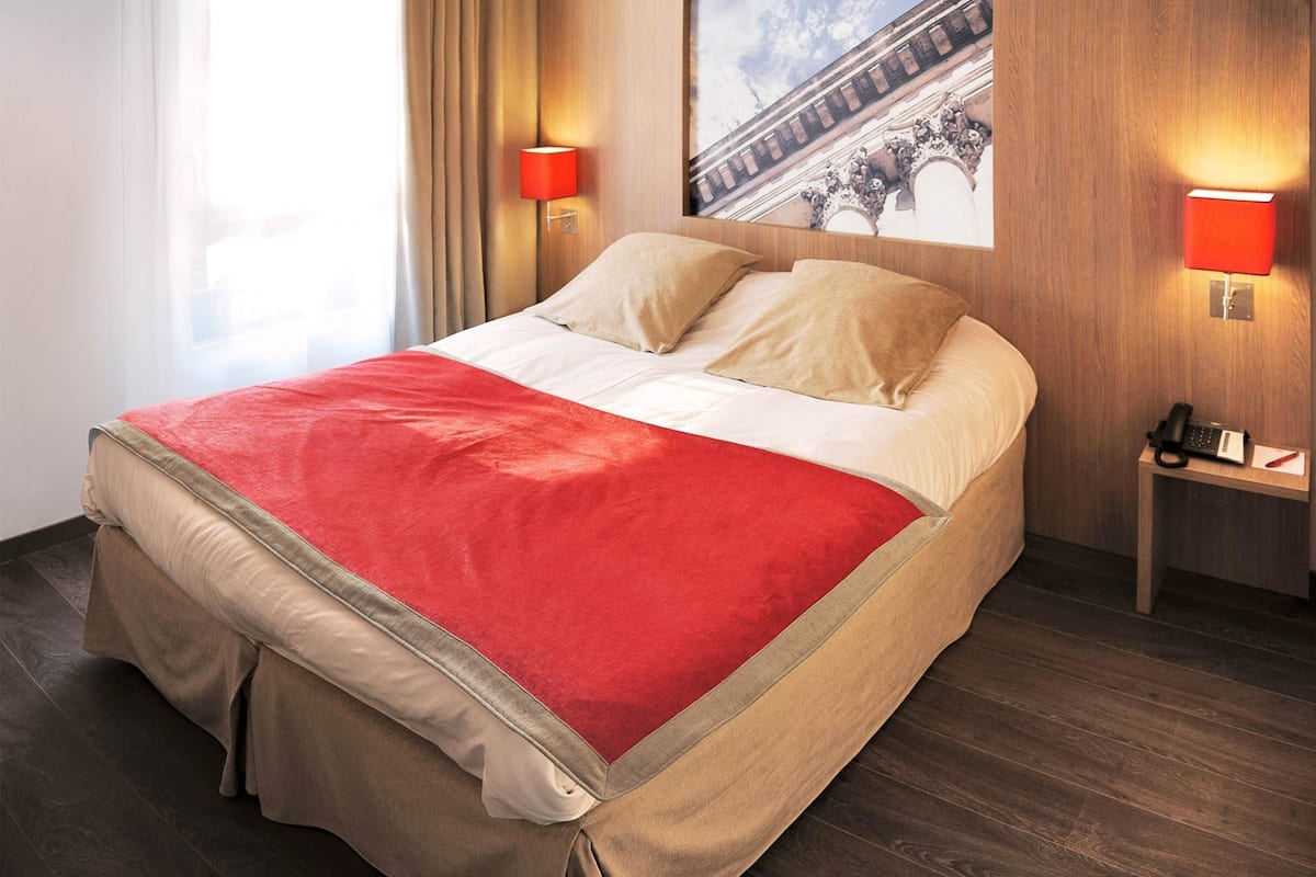 Une chambre d’hôtel avec un lit, une table de chevet, une lampe et un tableau au mur.