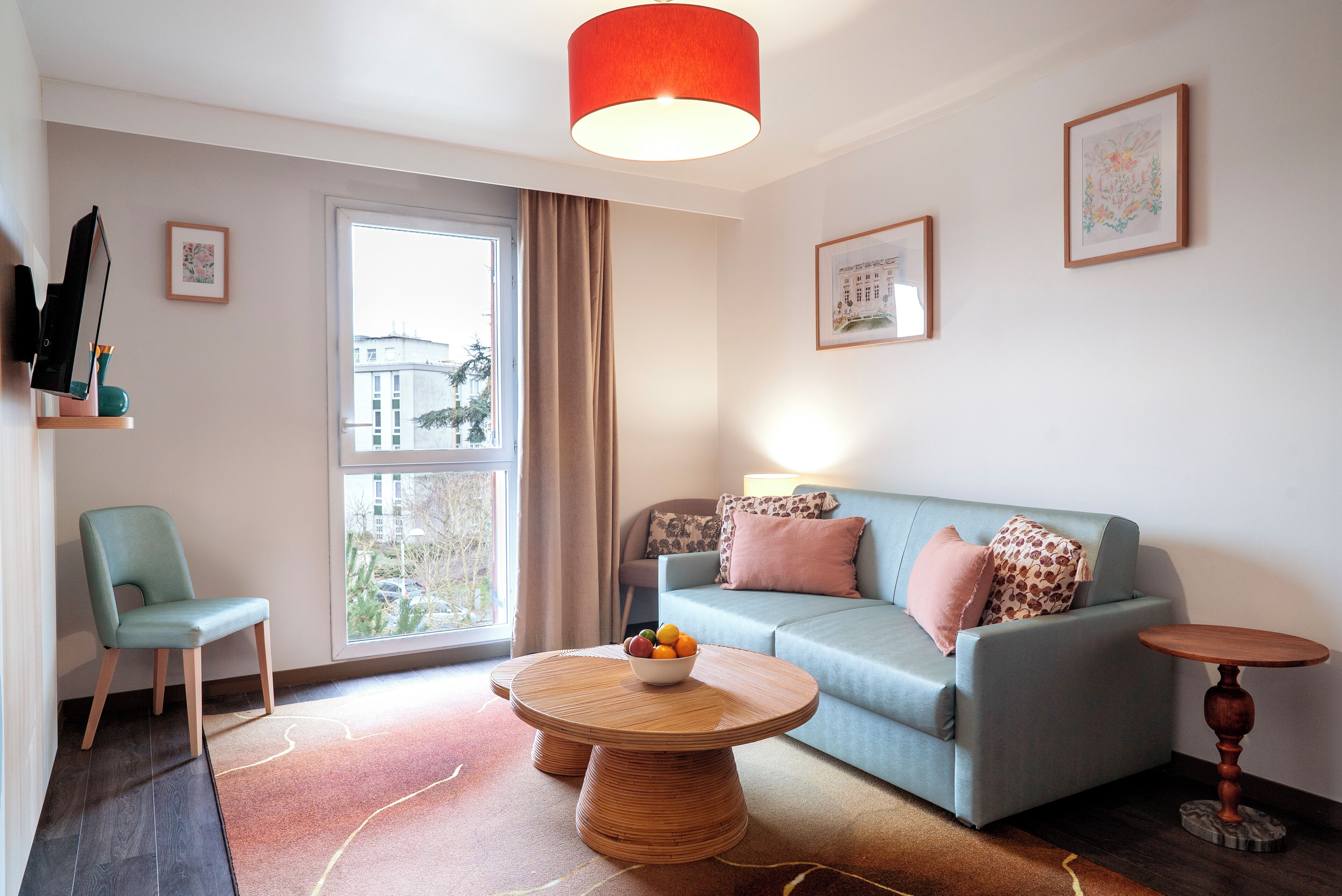 A modern living room with a sofa, a round coffee table with fruit, a chair, and a small table.