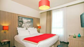 Habitación de hotel con cama, dos lámparas de noche, lámpara de techo roja, cabecero de madera, un cuadro, ventana con cortinas, cómoda de madera y televisión.