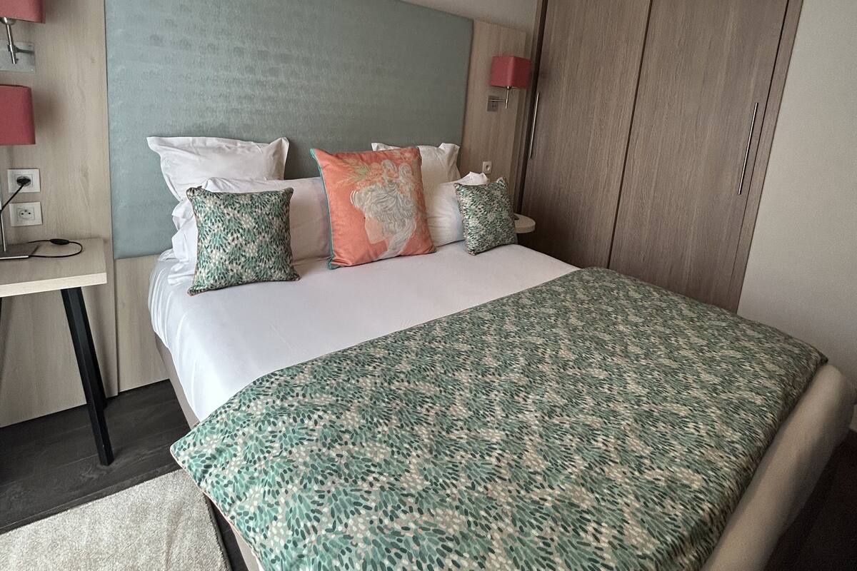 Une chambre d’hôtel comprenant un lit, des tables de chevet, une armoire et un luminaire au plafond.
