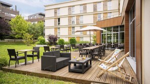 An outdoor patio area with wicker furniture, tables, and a wooden deck.