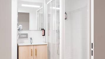 A modern bathroom with a glass shower enclosure, a wooden vanity, and a white sink.