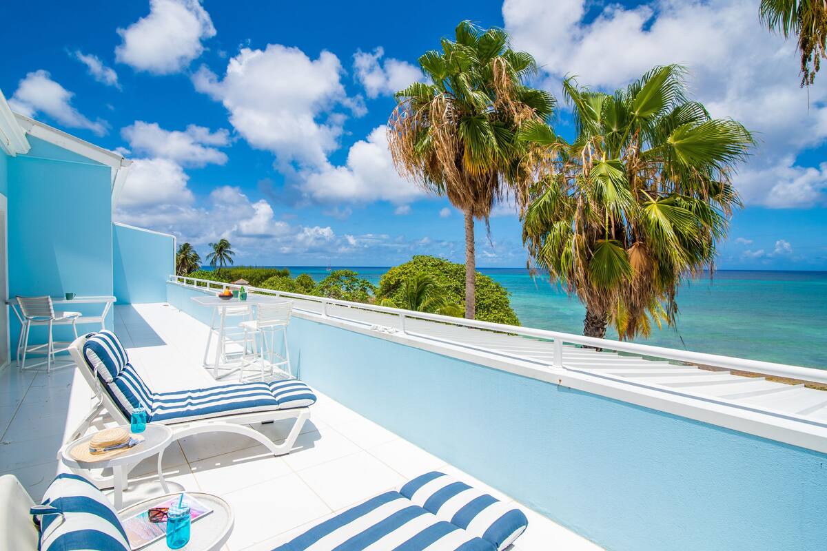 A poolside area with lounge chairs and a view of the ocean.