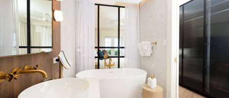 Une salle de bain moderne dotée d’une grande baignoire, d’un lavabo séparé et de toilettes.