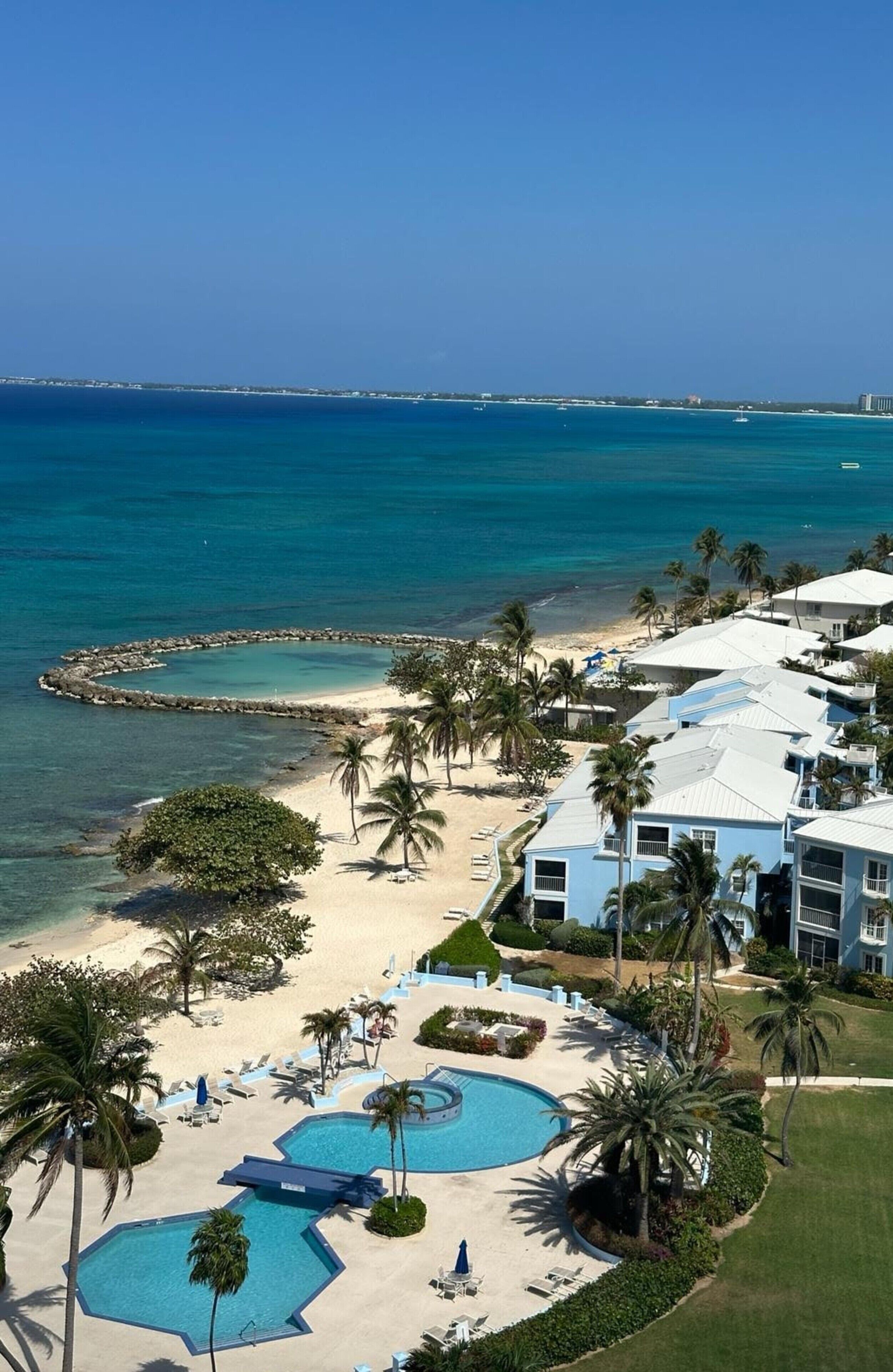 A resort with a beach, swimming pools, and palm trees.