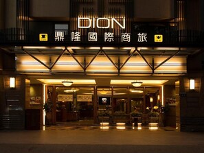 The exterior of a hotel with a prominent "DION" sign, a cafe symbol, and a sign indicating a restaurant. - Hotel Dion (Taichung)