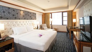 A hotel room with a large bed, a desk with a TV, a chair, and a window with curtains. - Hotel Dion (Taichung)