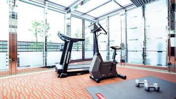 A gym with treadmills, an elliptical, and dumbbells on a patterned carpet.