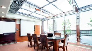 A conference room with a glass table, chairs, a laptop, and a projector screen. - Hotel Dion (Taichung)