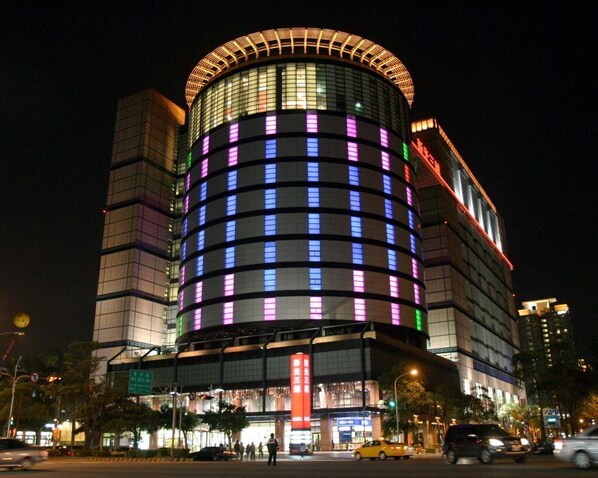 Un hotel moderno con fachada curva y ventanas iluminadas.