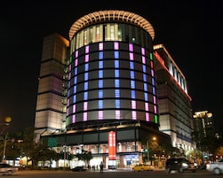 A modern hotel with a curved facade and illuminated windows.