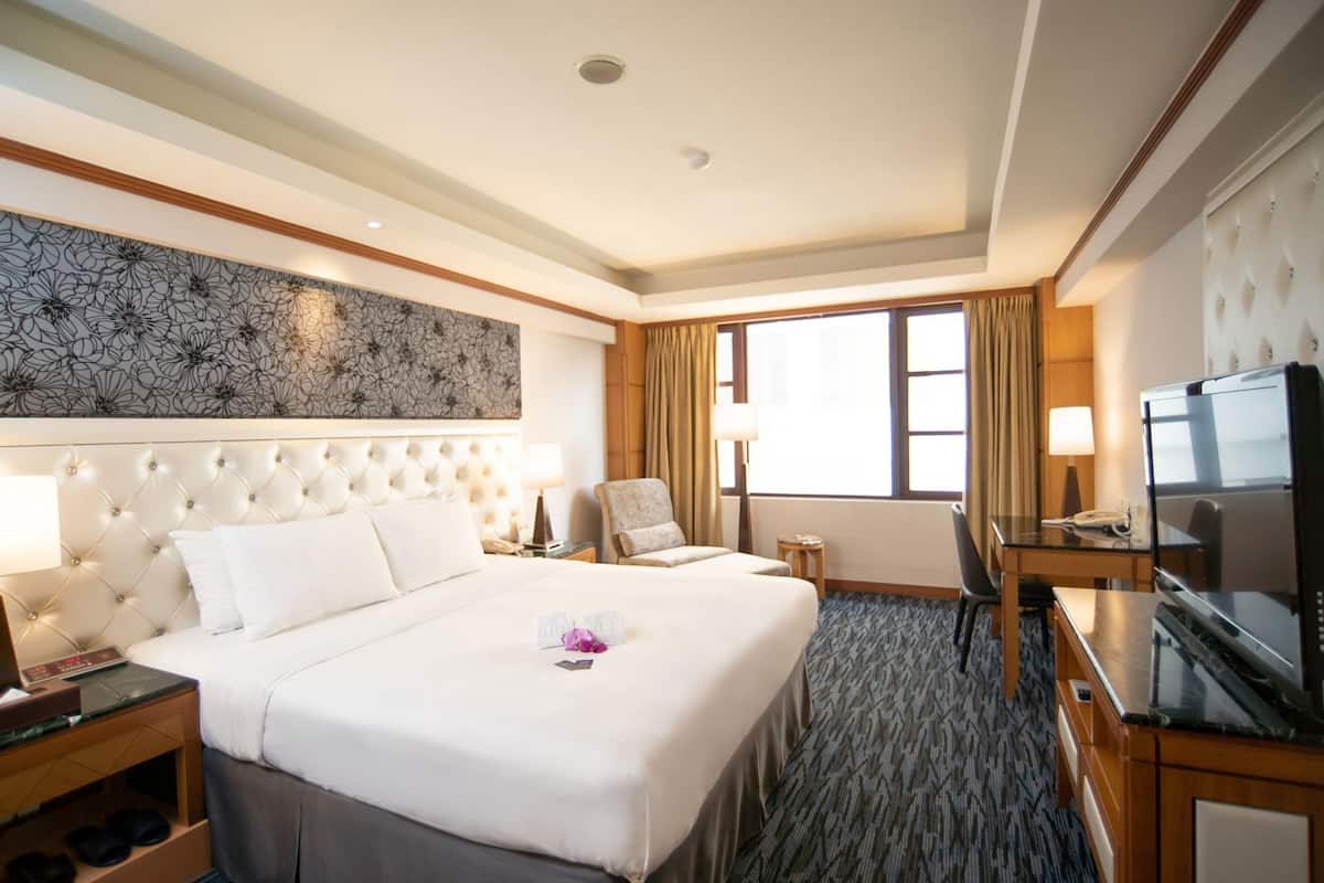 A hotel room with a large bed, a television, a desk, and a chair.