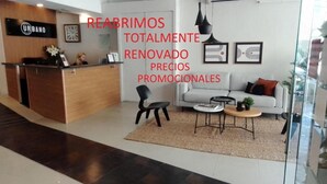 A modern hotel lobby with a reception desk, a sofa, a coffee table, and a chair. - Urbano Hotel (Montevideo)