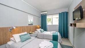 A hotel room with two beds, a TV, a window with curtains, and a mounted TV on the wall. - Urbano Hotel (Montevideo)