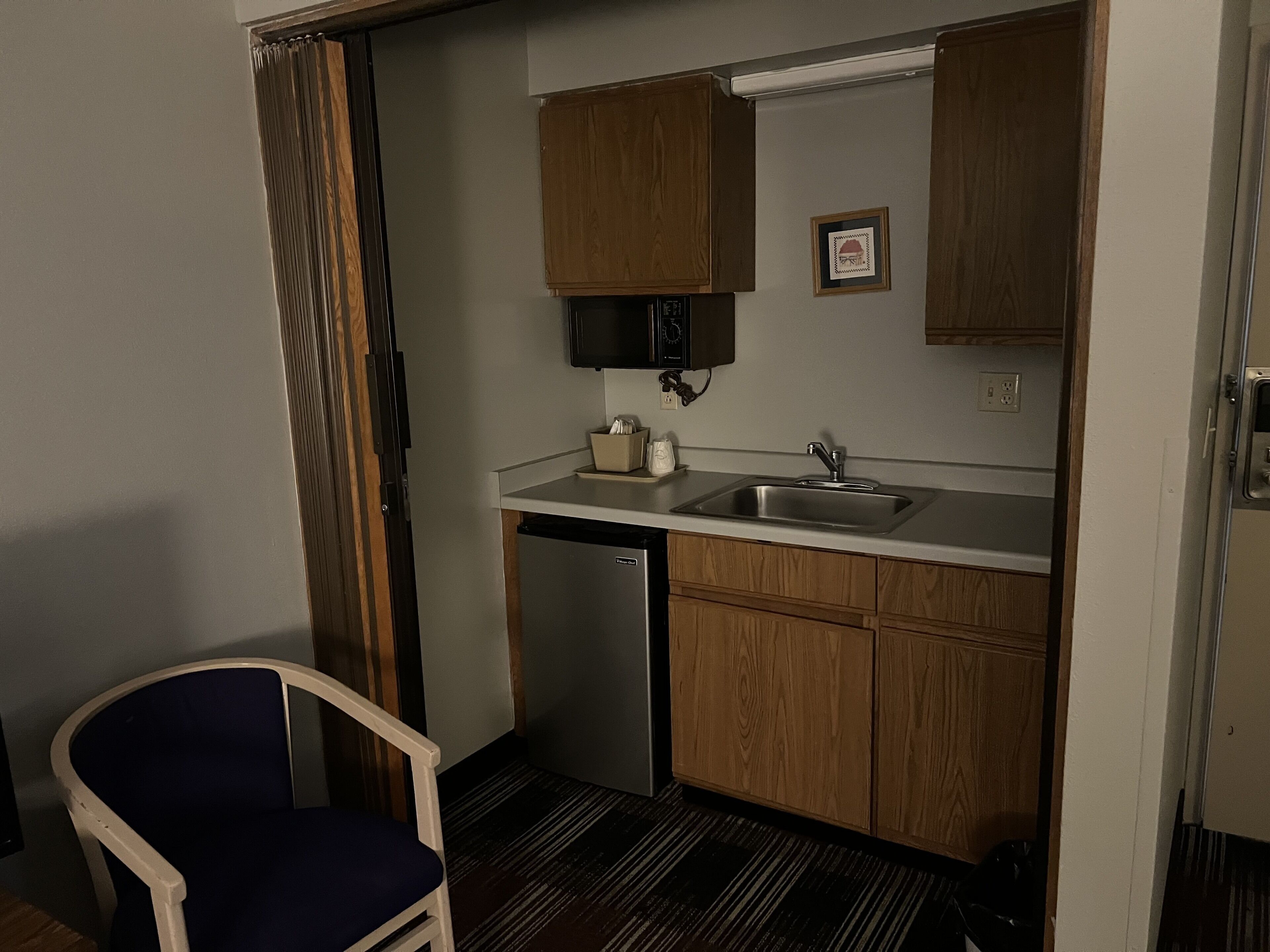 A compact kitchen with wooden cabinets, a stainless steel sink, and a built-in microwave.