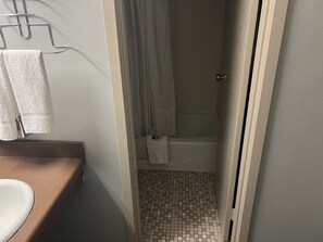A bathroom with a toilet, a towel rack, a shower curtain, and a tiled floor.
