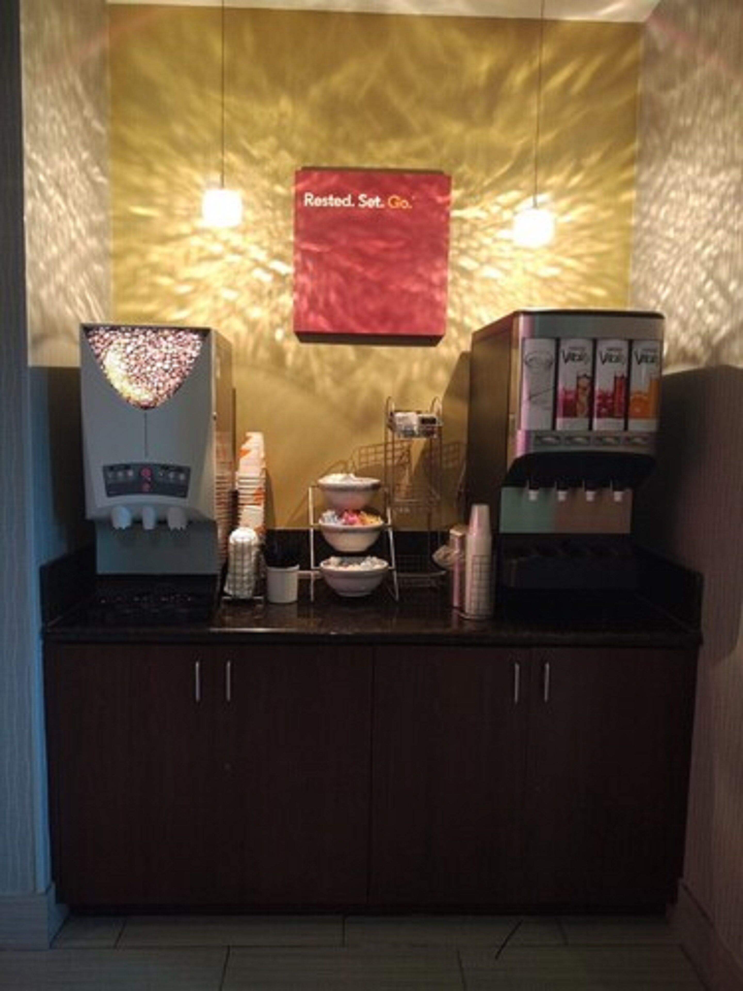 A coffee station with a heart-shaped light, a vending machine, and a sign that reads "Rested. Set. Go."