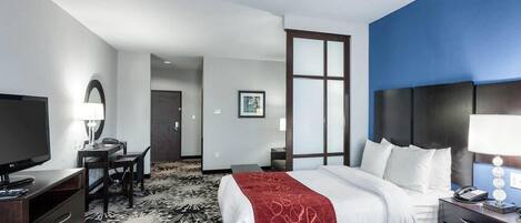 A hotel room with a bed, a desk, a TV, and a nightstand.