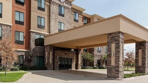 A multi-story hotel with a stone facade, a covered entrance, and a clear sky.