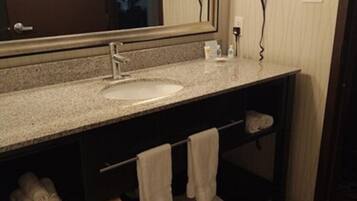 Un baño con lavamanos, espejo, toallero y secador de pelo.