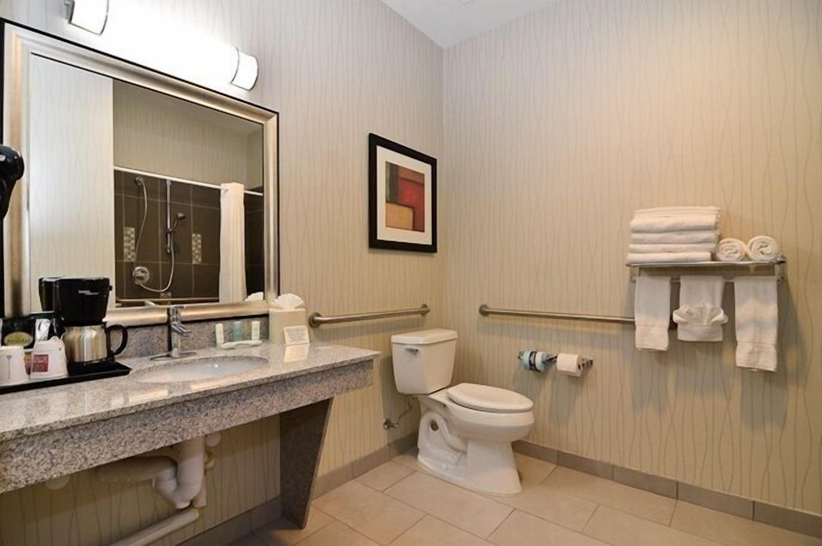 A bathroom with a sink, mirror, toilet, and towel rack.