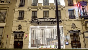 Um edifício com vários andares, entrada central, grandes janelas e varandas.