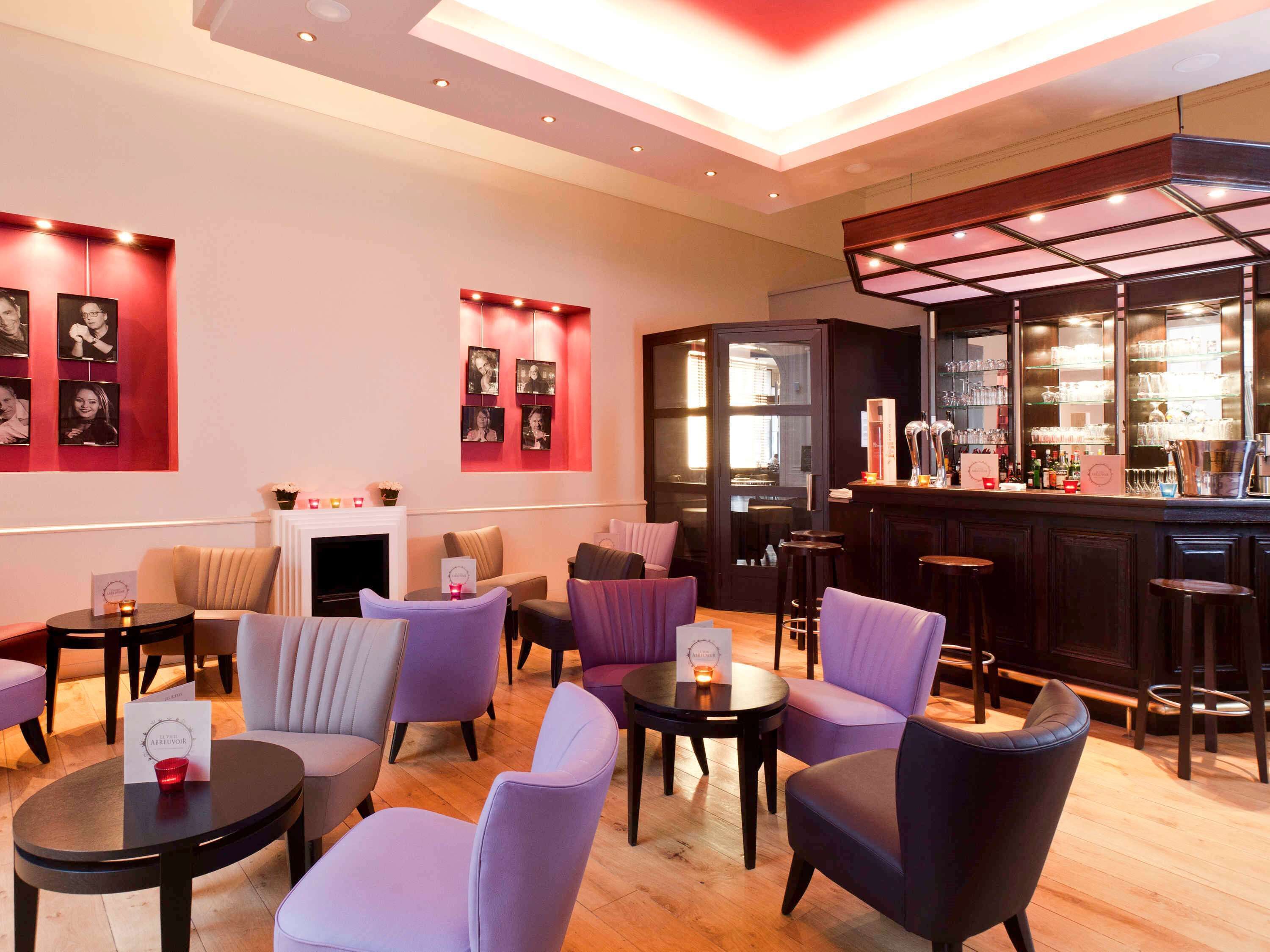 A modern lounge area with seating, a fireplace, and a bar with glassware.